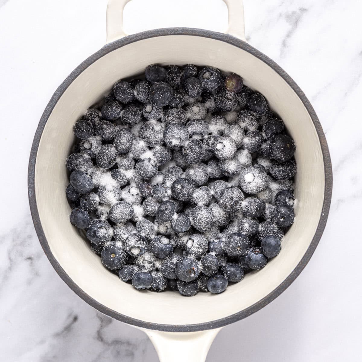 Blueberries and sugar in a pot.