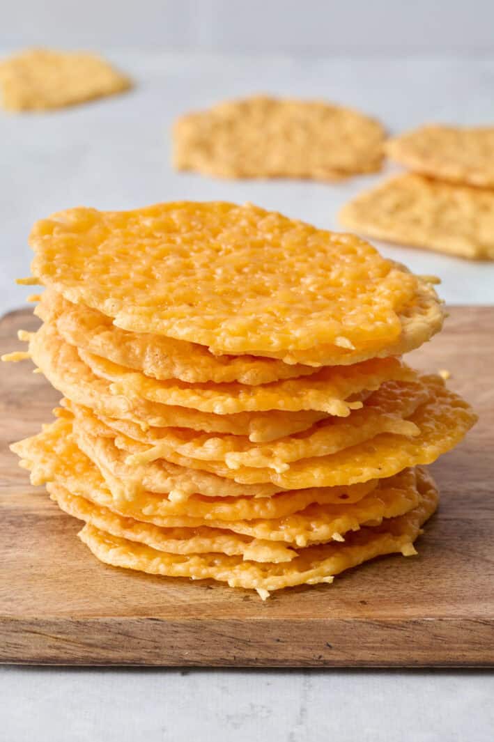 Cheese crisps stacked up with a few extra scattered in background.