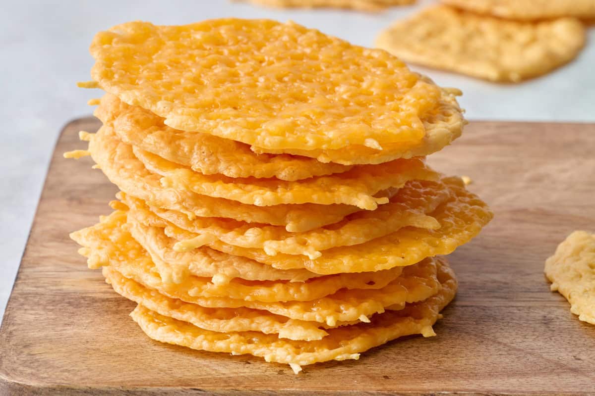 Cheese crisps stacked up with a few extra scattered in background.