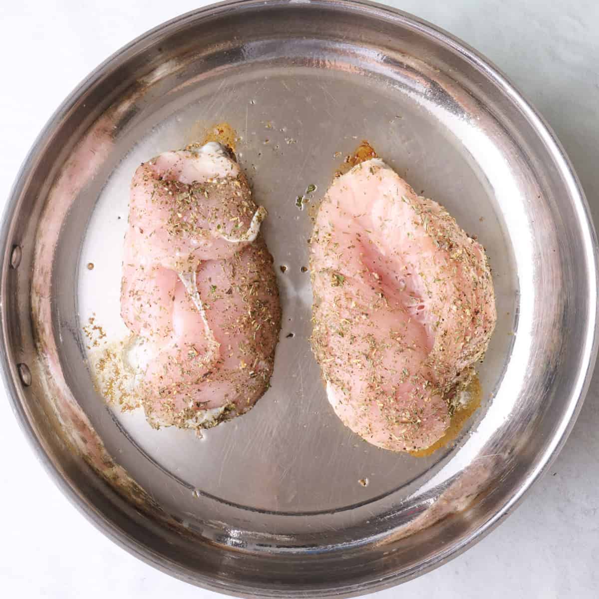 Seasoned chicken added to an oiled pan.