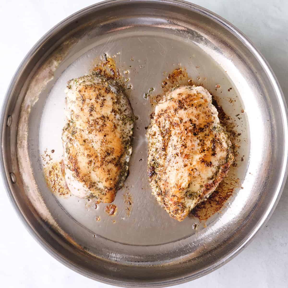 Chicken breasts after flipping in a skillet.