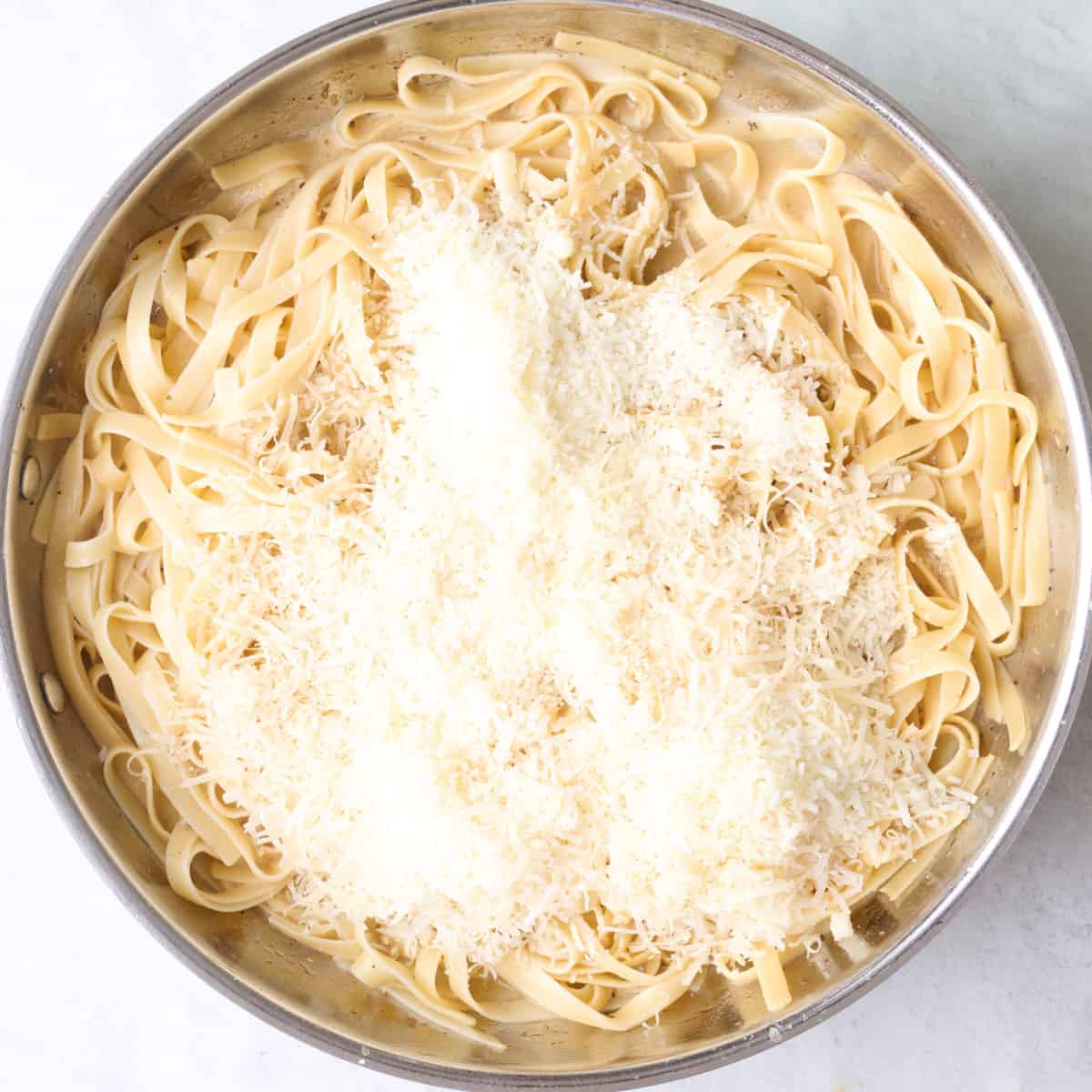 Cooked pasta, pasta water, and parmesan added to skillet on top of sauce.