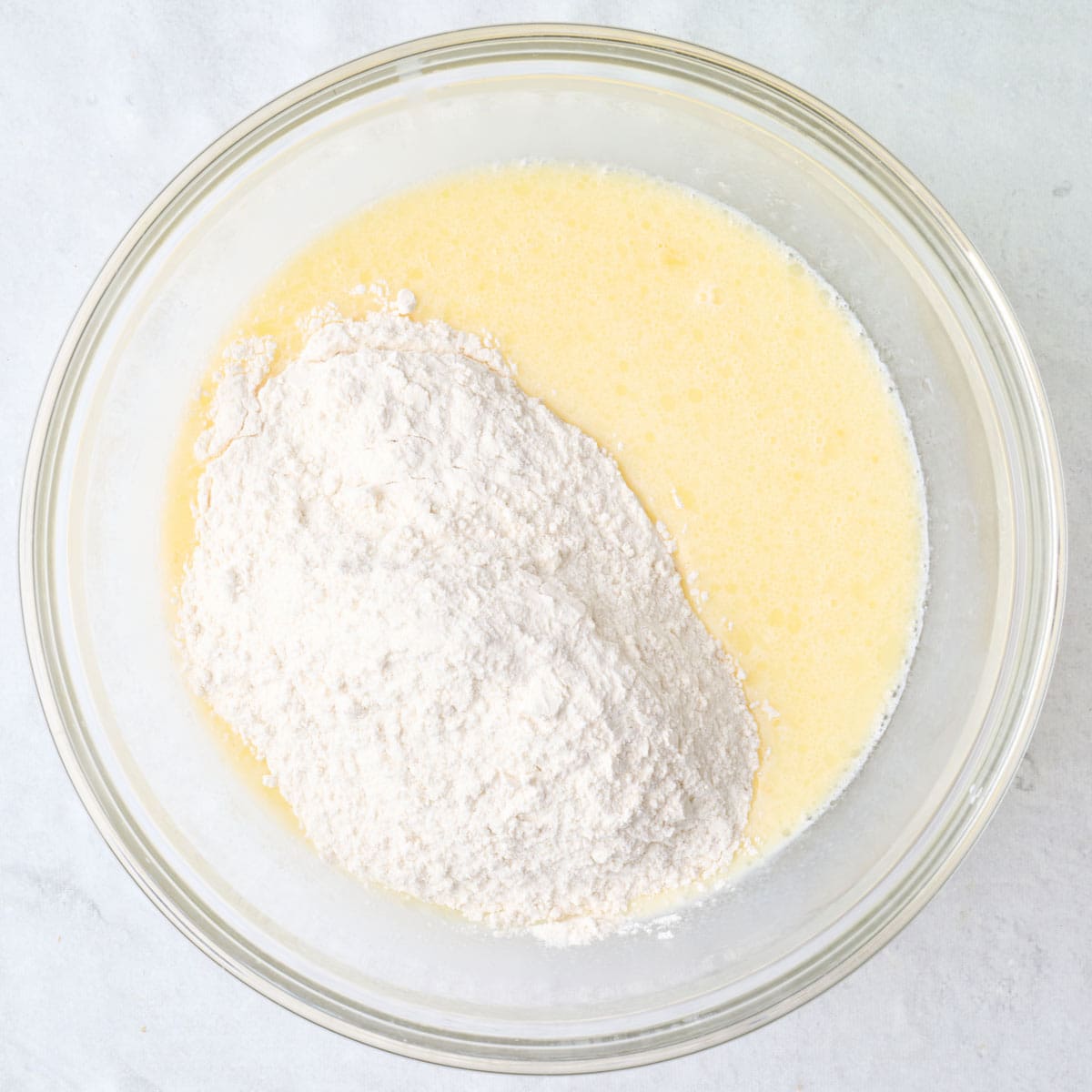 Egg mixture in a bowl with dry ingredients added on top.