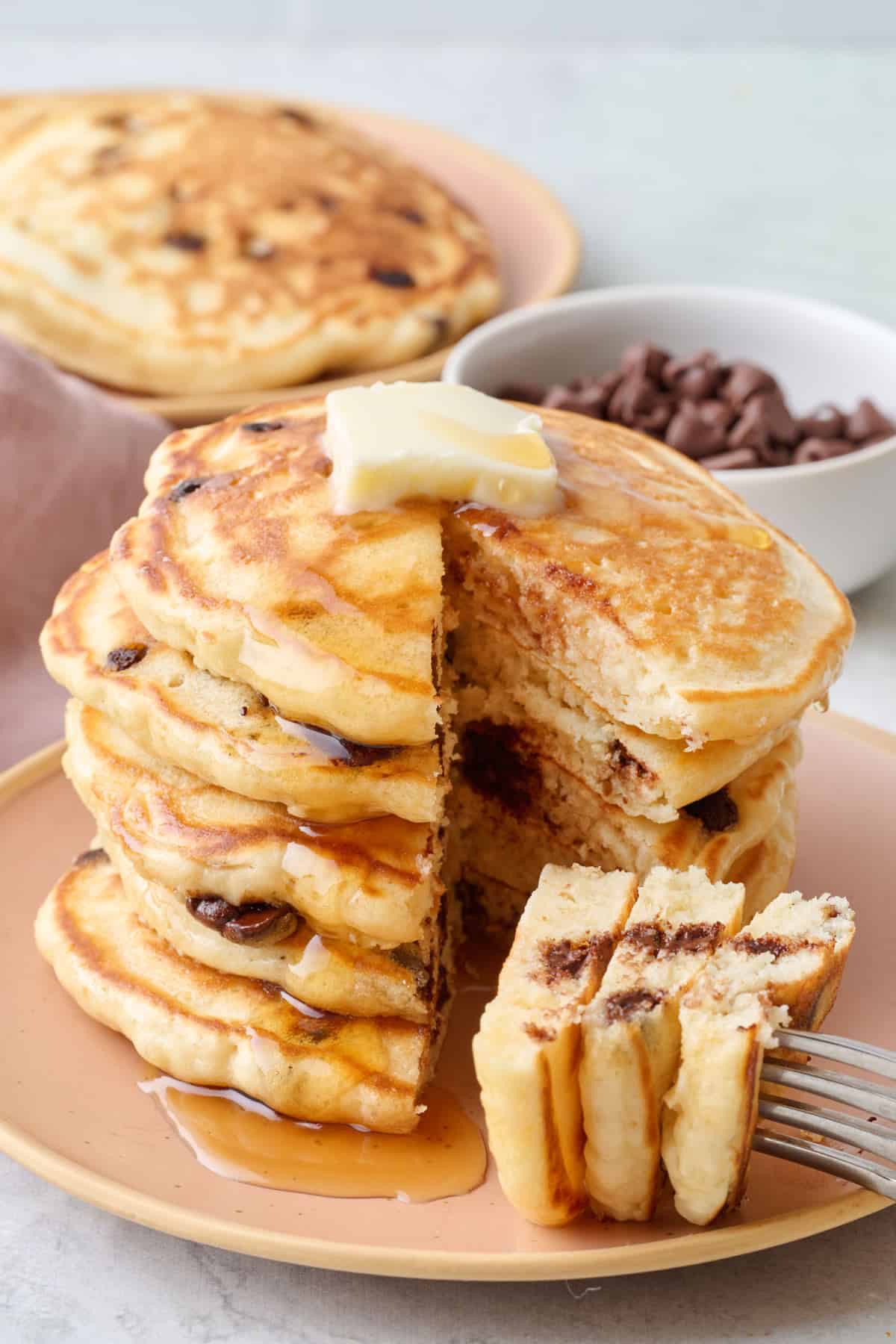 Easy chocolate chip pancakes recipe on a plate with a bite cut out of stack.