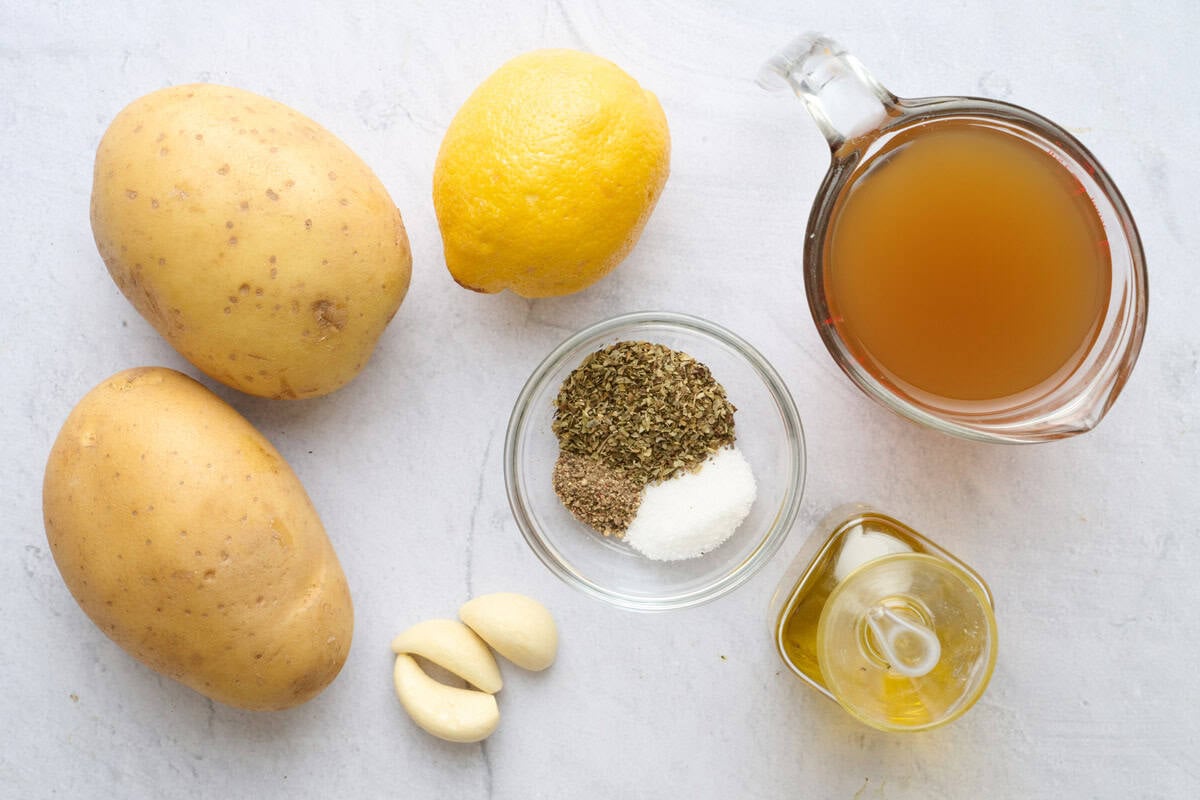 Ingredients for recipe: potatoes, lemon, garlic cloves, seasonings, broth and oil.
