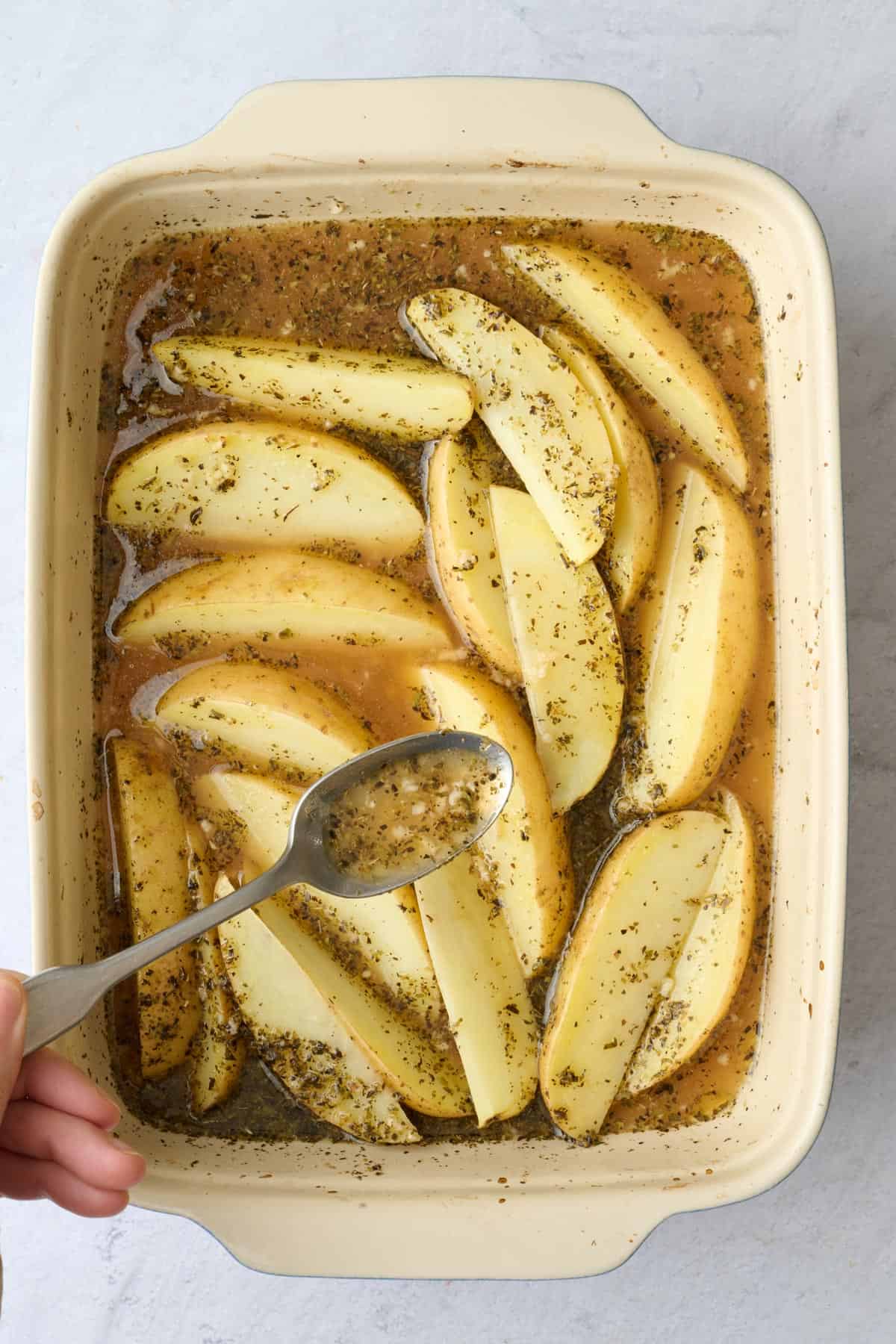 Basting potatoes halfway through cooking with a spoon.