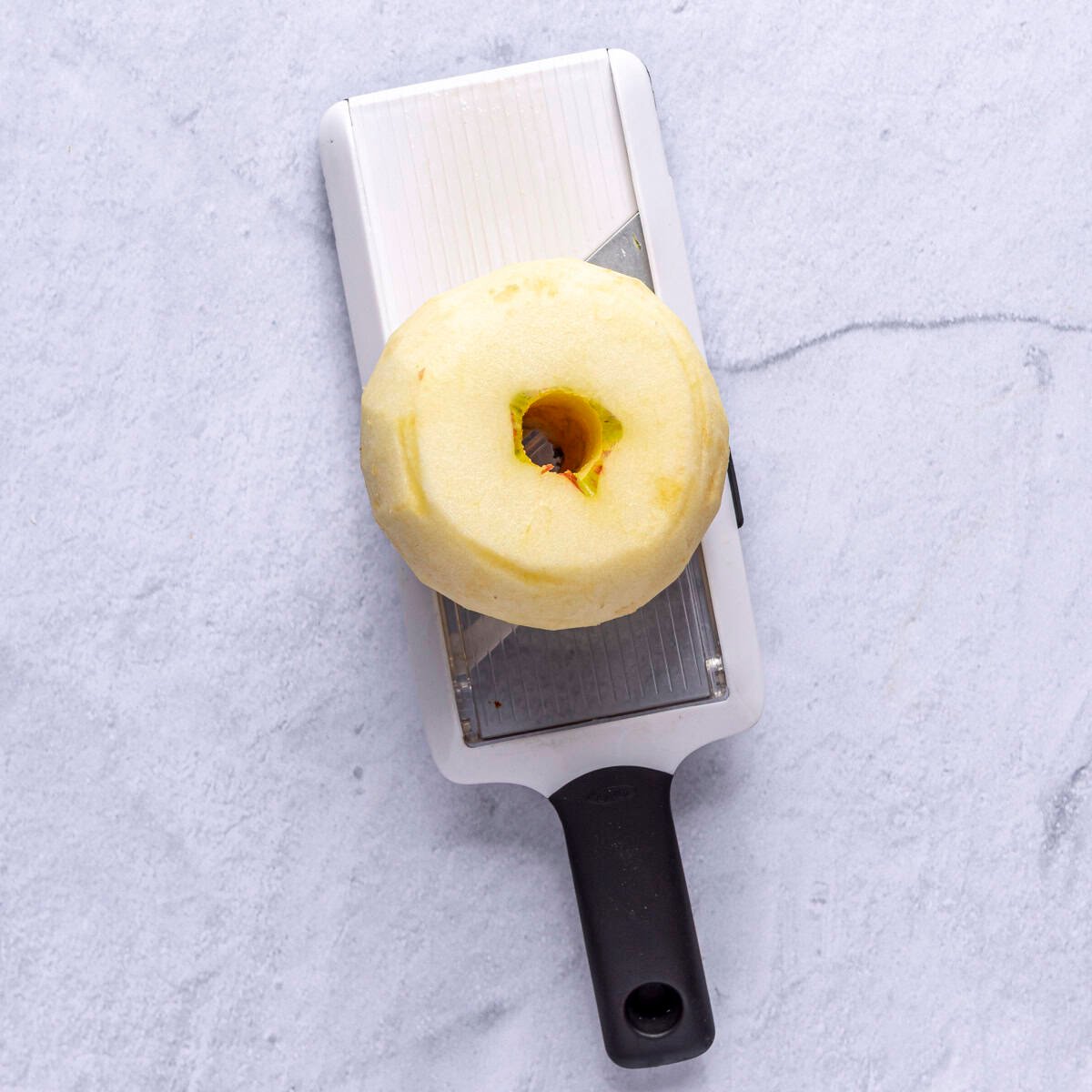 Peeled and cored apple on a mandolin.