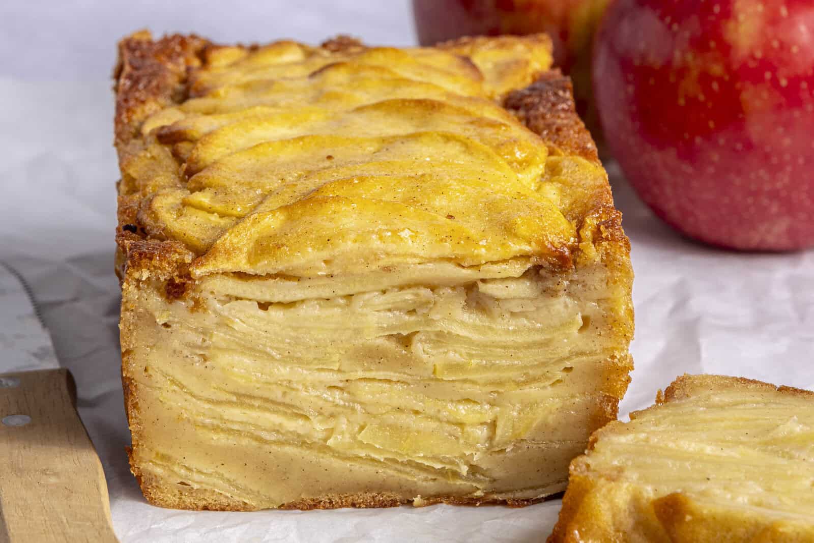 Invisible apple cake recipe with a slice removed showing layers of custard and thin apple slices.