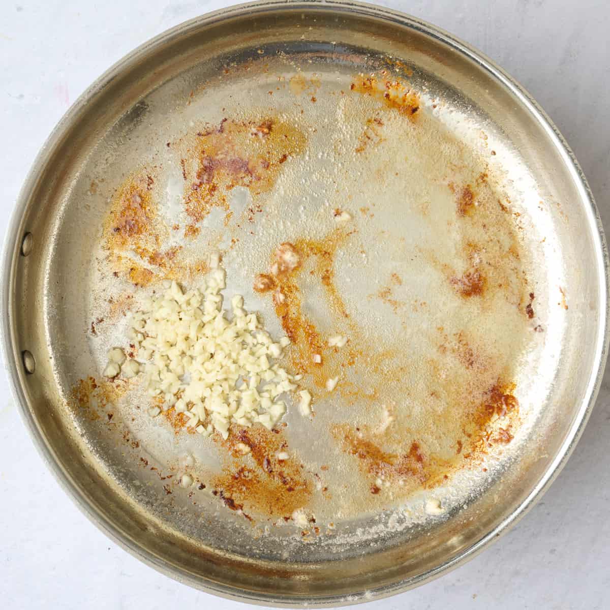 Chicken removed from skillet with garlic added.