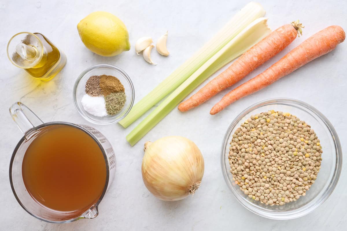 ingredients for recipe before prepping: oil, lemon, garlic, spices, broth, celery, carrots, onion, and green lentils.