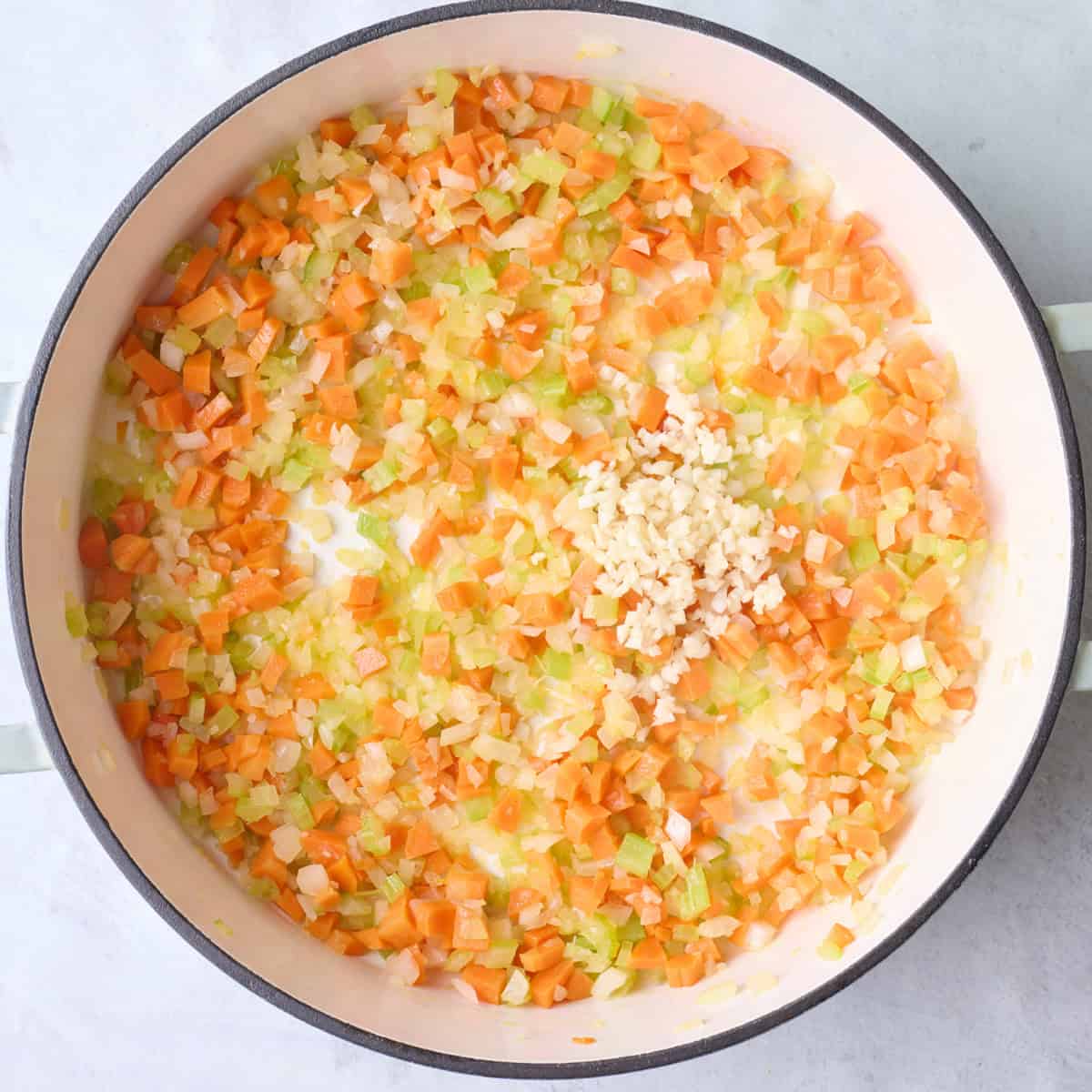 Onions, carrots and celery in pot after cooking with garlic added.