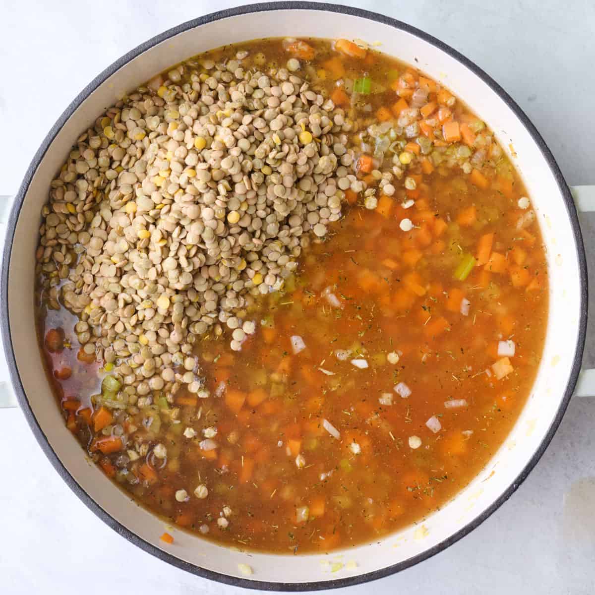 Broth and dried lentils added to pot with cooked vegetables.