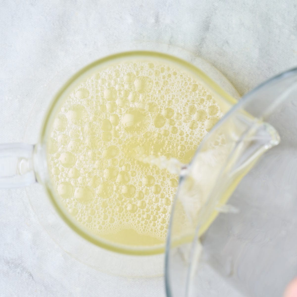 Lime juice in a pitcher with simple syrup being poured in.