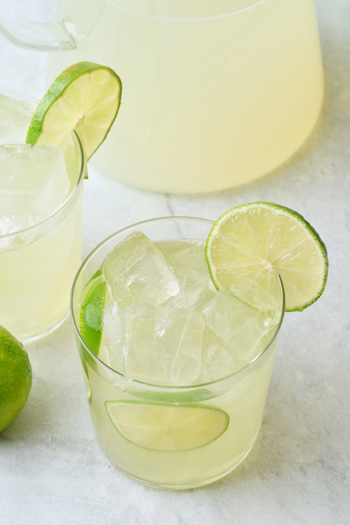 Homemade limeade recipe in two glasses with pitcher nearby.