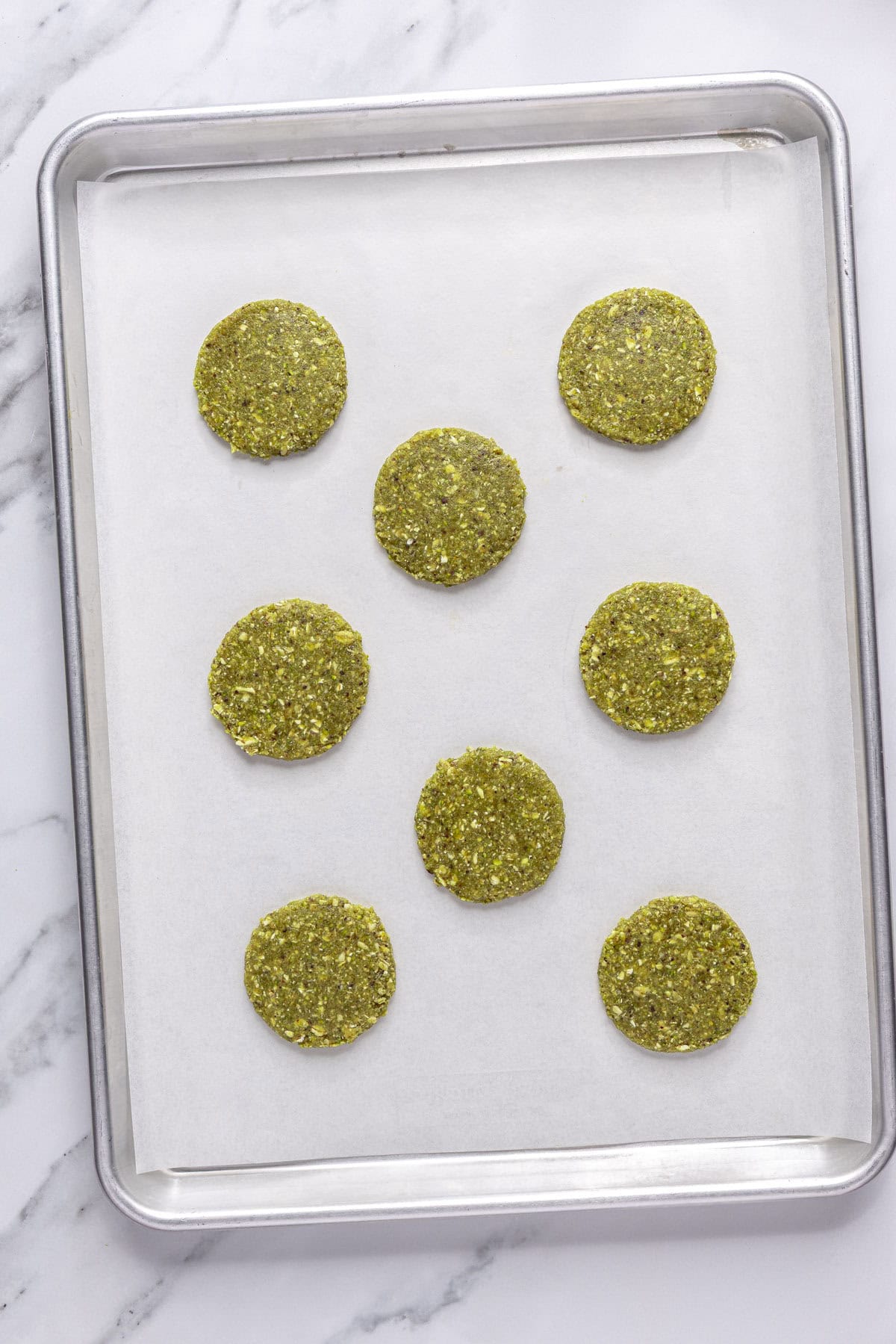 Cookies scooped and flattened on a parchment lined baking sheet before baking.