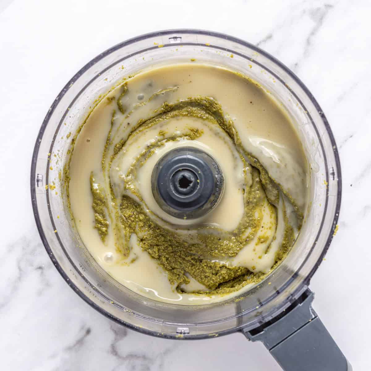 Pistachio paste in a food processor with sweetened condensed milk added.