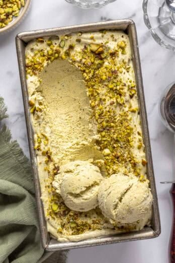 Easy pistachio ice cream recipe in a dish topped with chopped nuts and a few scoops of ice cream on top.