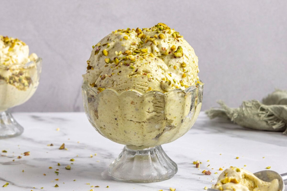 Pistachio ice cream scooped into a bowl, topped with extra pistachios.