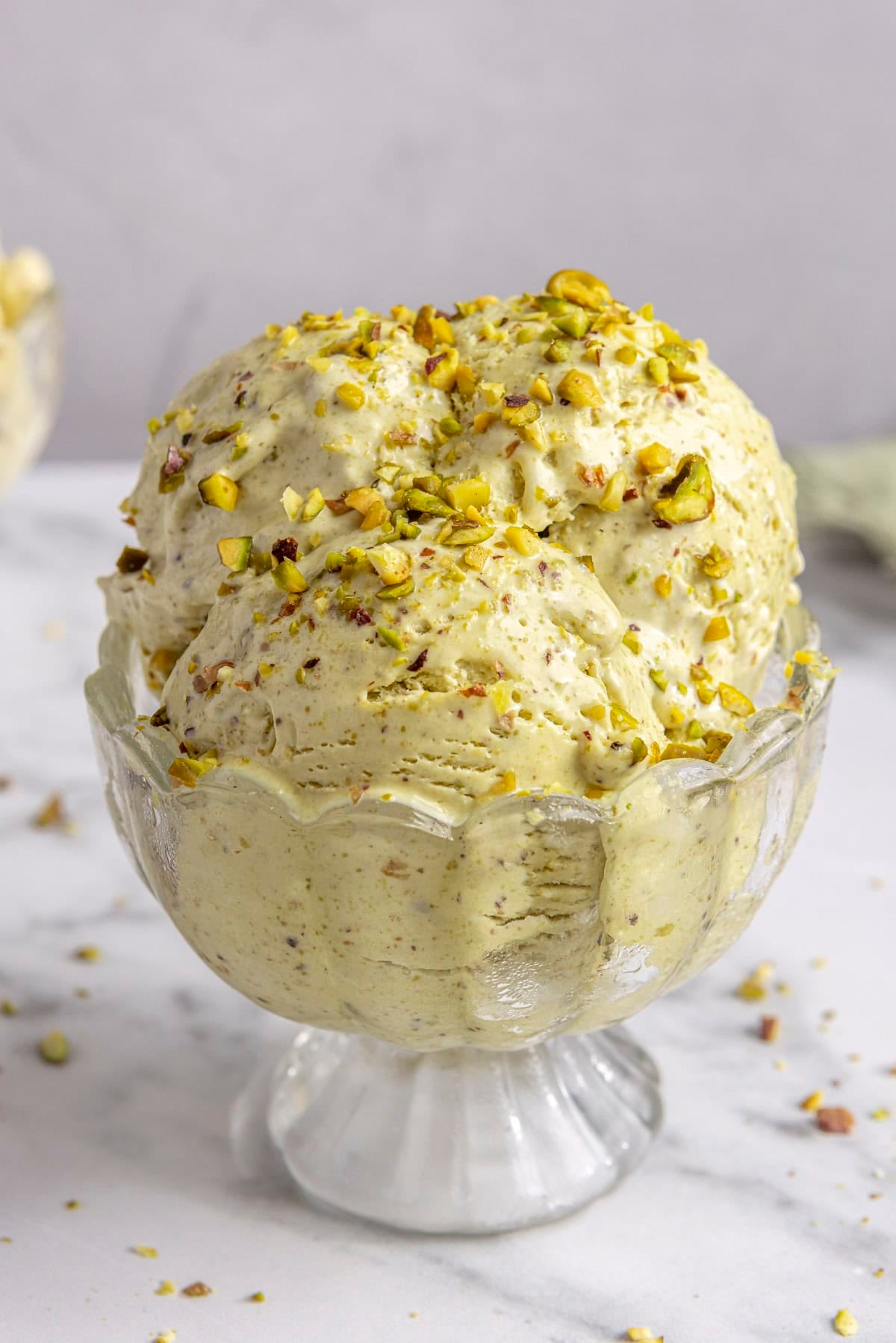 Pistachio ice cream scooped into a bowl, topped with extra pistachios