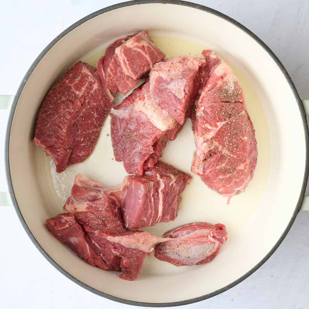 Seasoned beef chunks in an oiled dutch oven.
