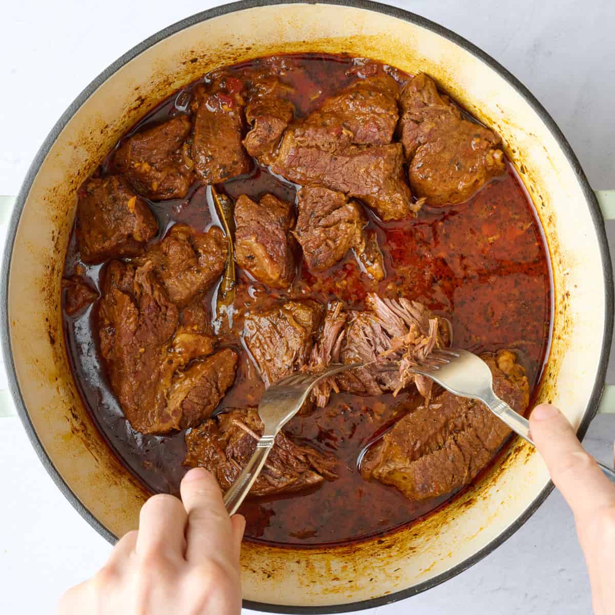 After beef has cooked with a fork shredding off a piece to show doneness.
