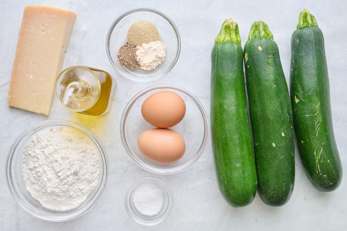 Ingredients for recipe: block of parmesan, flour, oil, seasonings, eggs, salt, and 3 zucchinis.