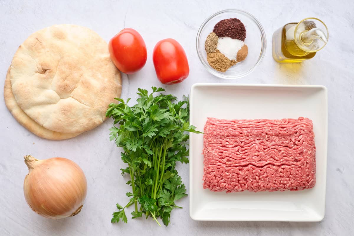 Ingredients for recipe: pita, onion, tomatoes, spices, parsley, ground beef, and oil.