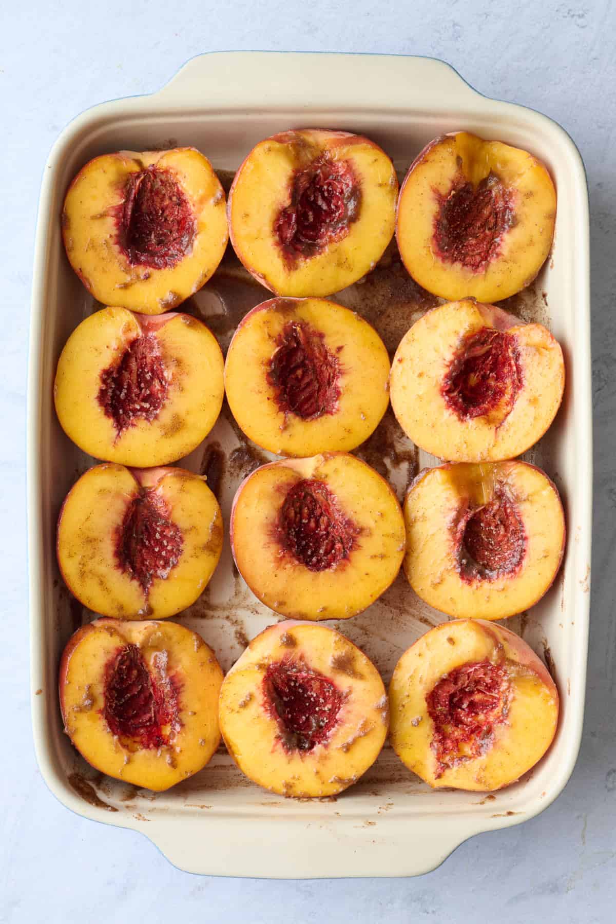 Peach halves in a baking dish before baking.