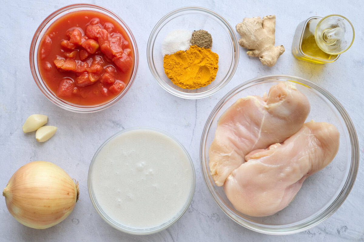 Ingredients for recipe: diced tomatoes, spices, garlic, onion, coconut milk, chicken breast, ginger, and oil.