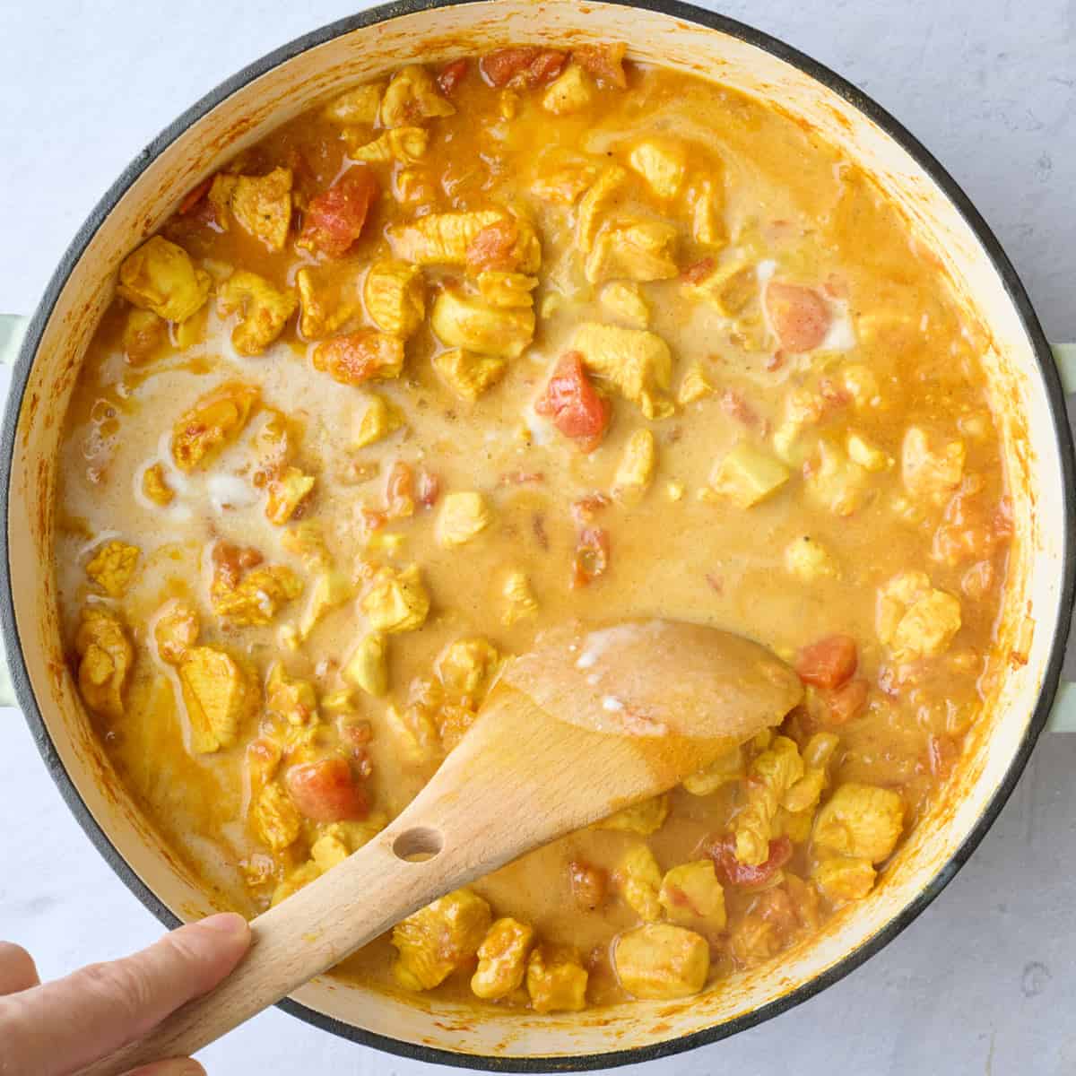 Wood spoon stirring in coconut milk.