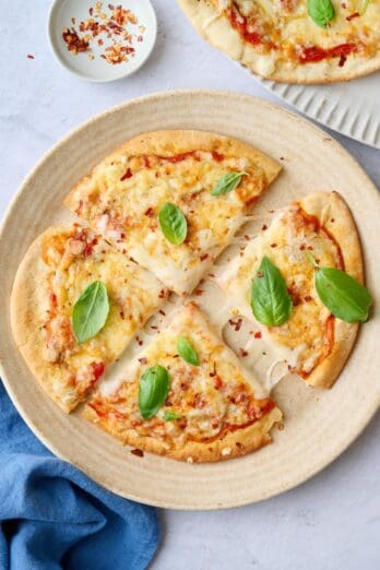 Best pita pizza recipe cut into quarters on a plate with pulled melty cheese.