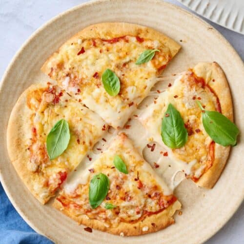 Best pita pizza recipe cut into quarters on a plate with pulled melty cheese.