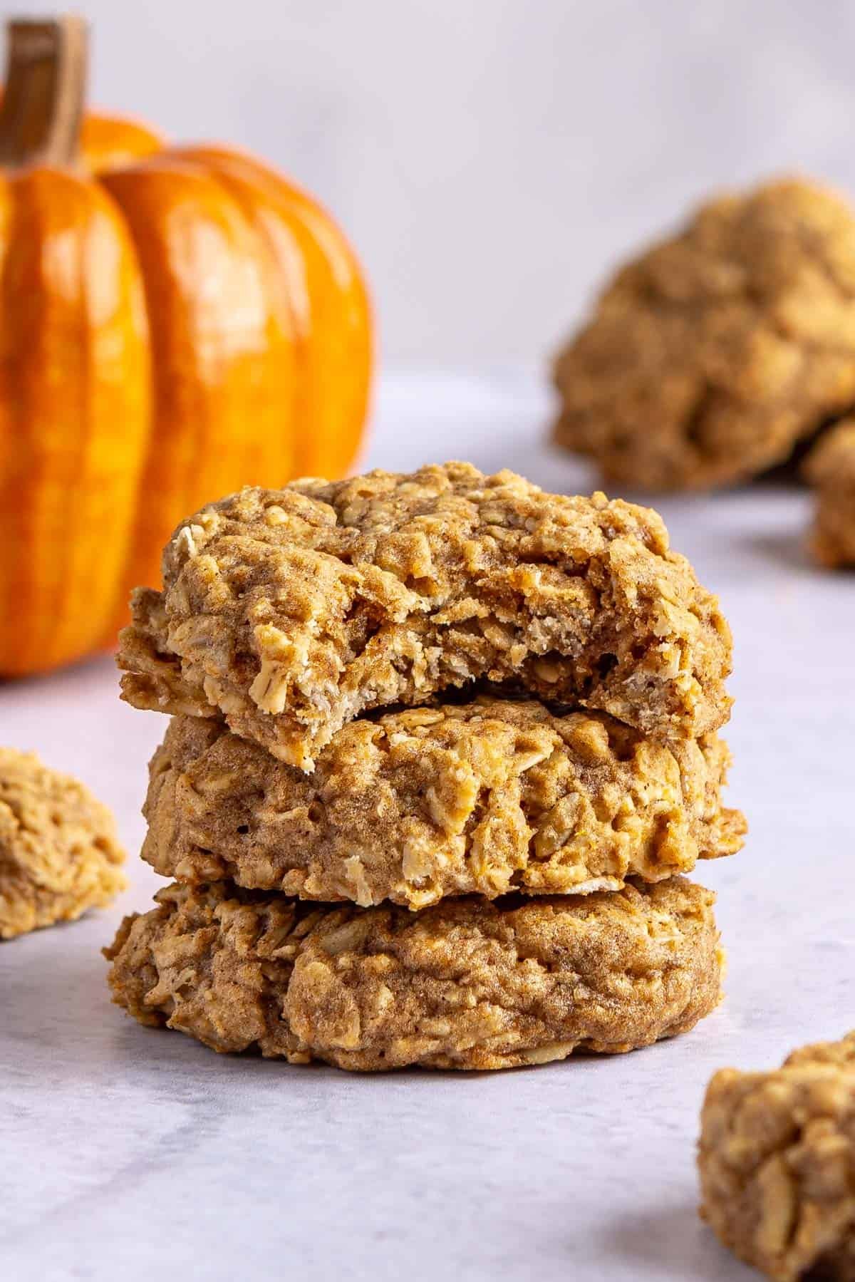 A few pumpkin oatmeal cookies stacked up with a bite taken out of one.