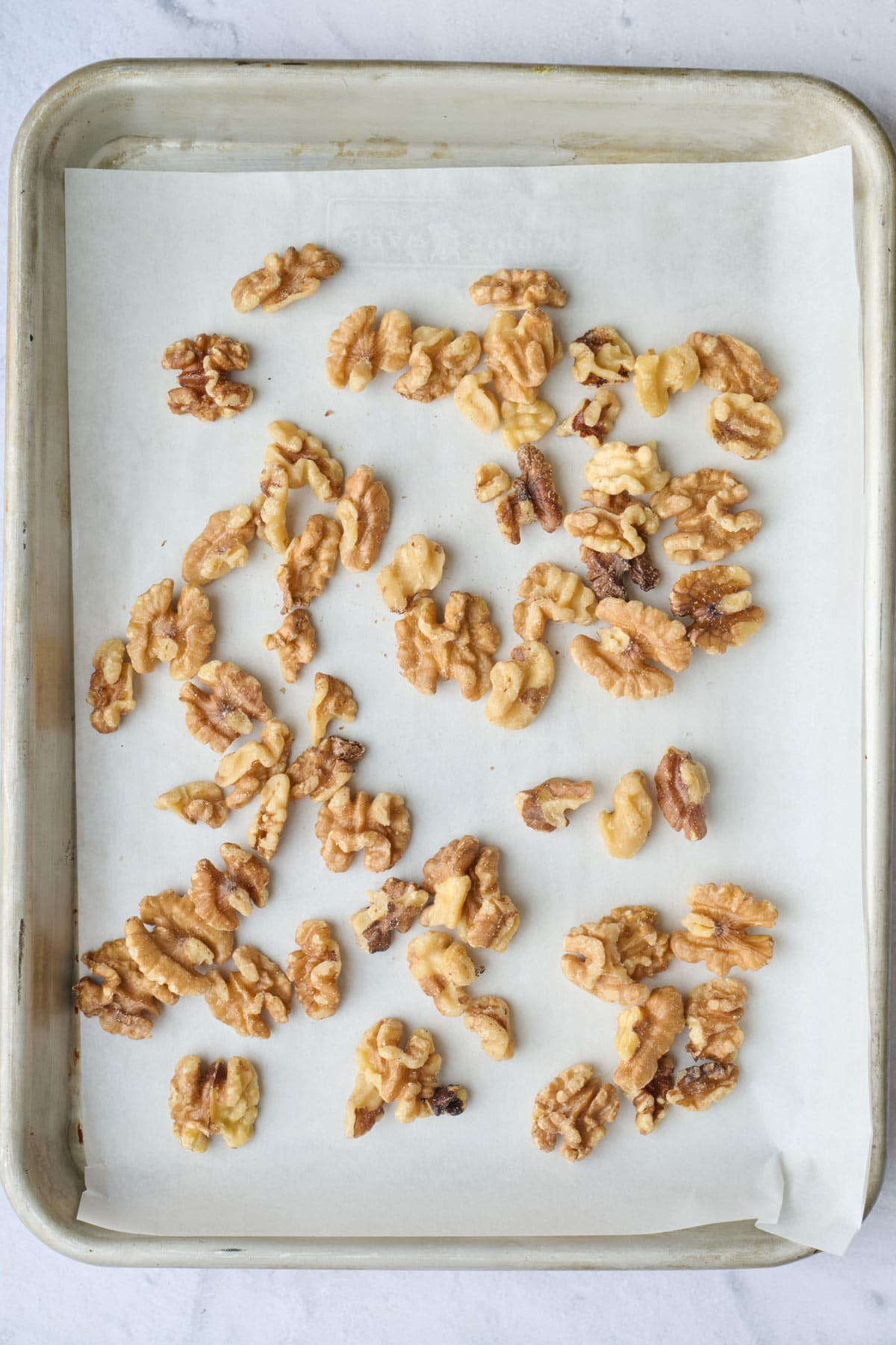 Walnuts on a parchment lined baking sheet.