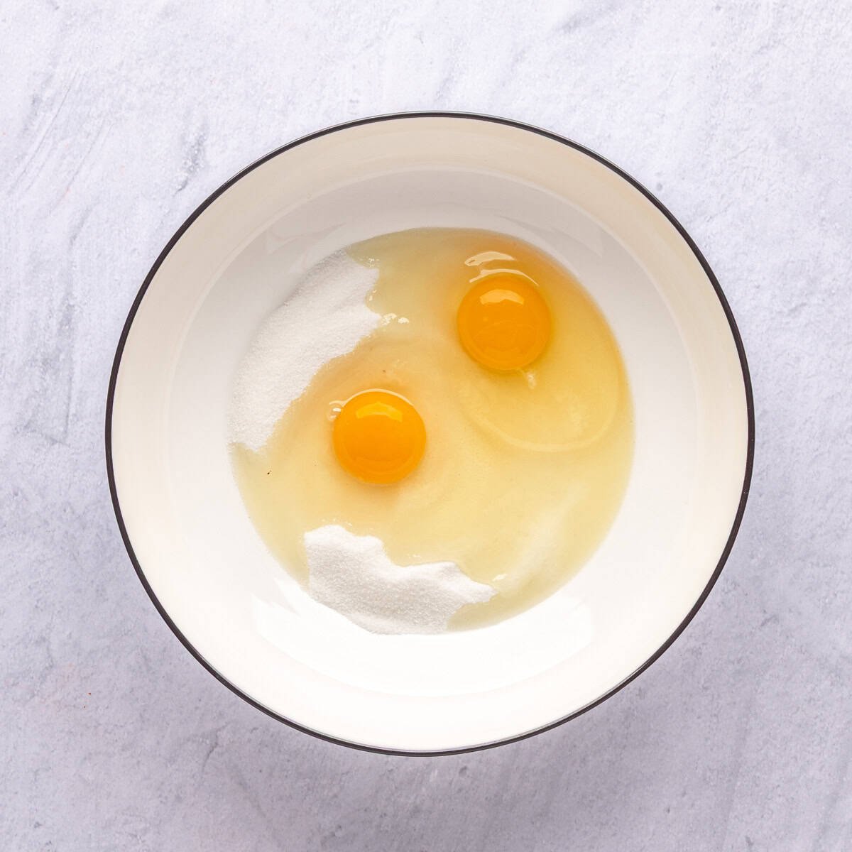 Eggs and sugar in a bowl before mixing.