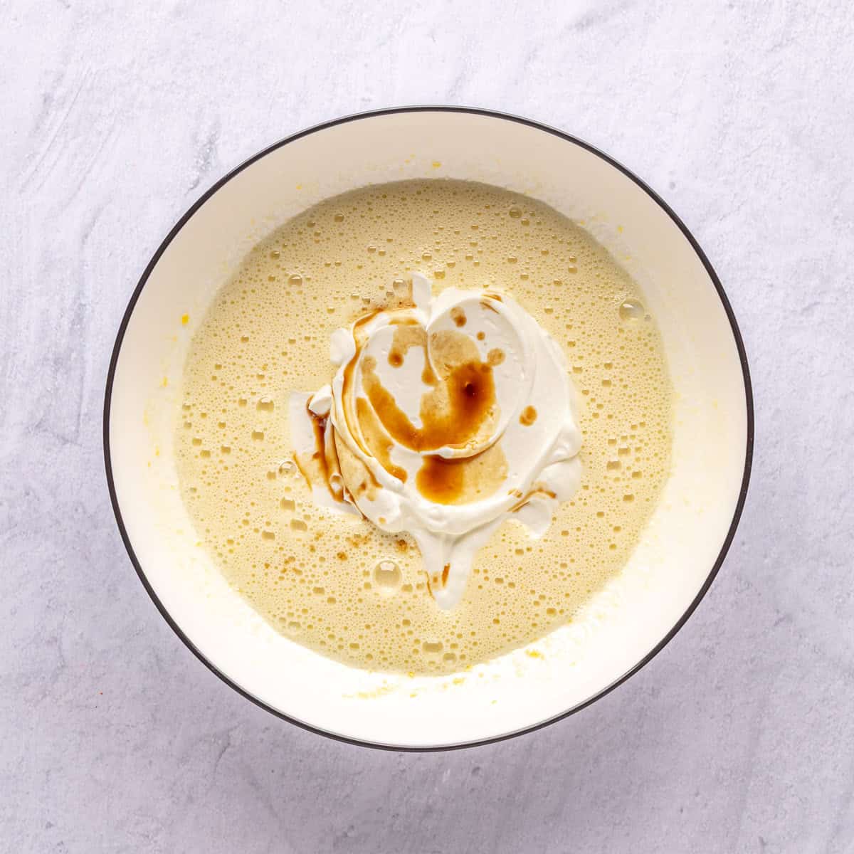 Egg and sugar whisked in a bowl with Greek yogurt and vanilla added.