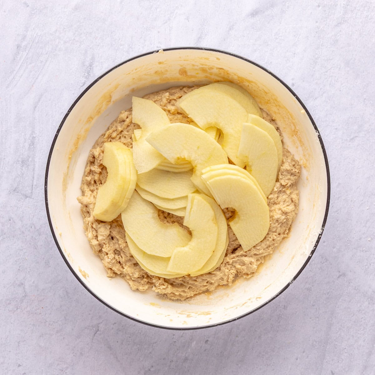 Apple slices added on top of apple cake batter.