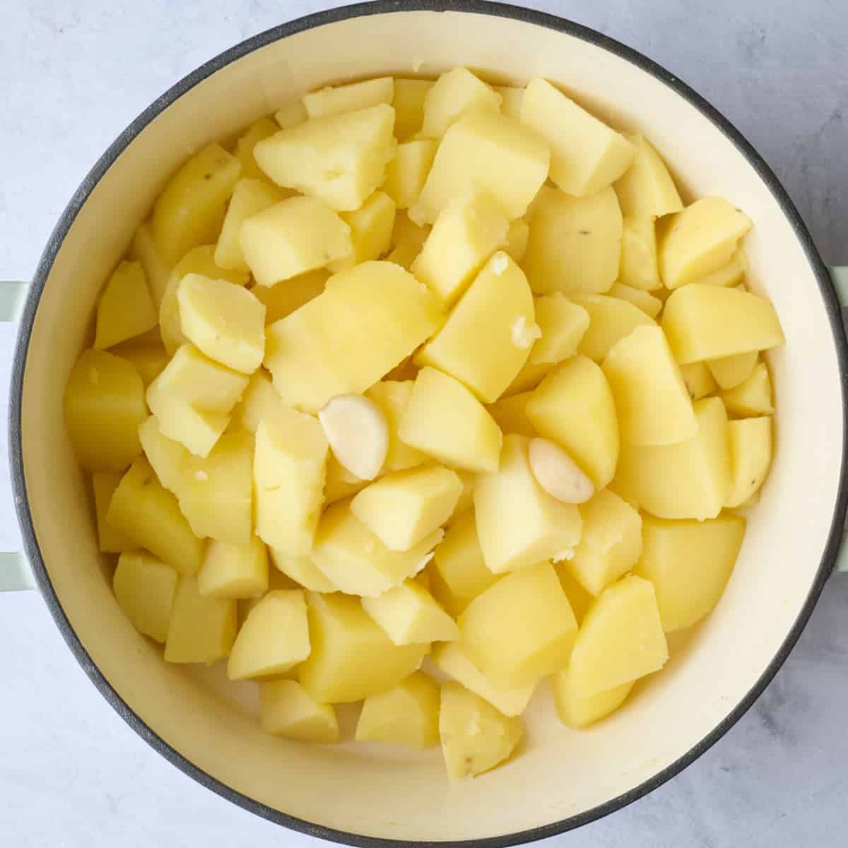 Cooked potatoes and garlic cloves in pot after draining.