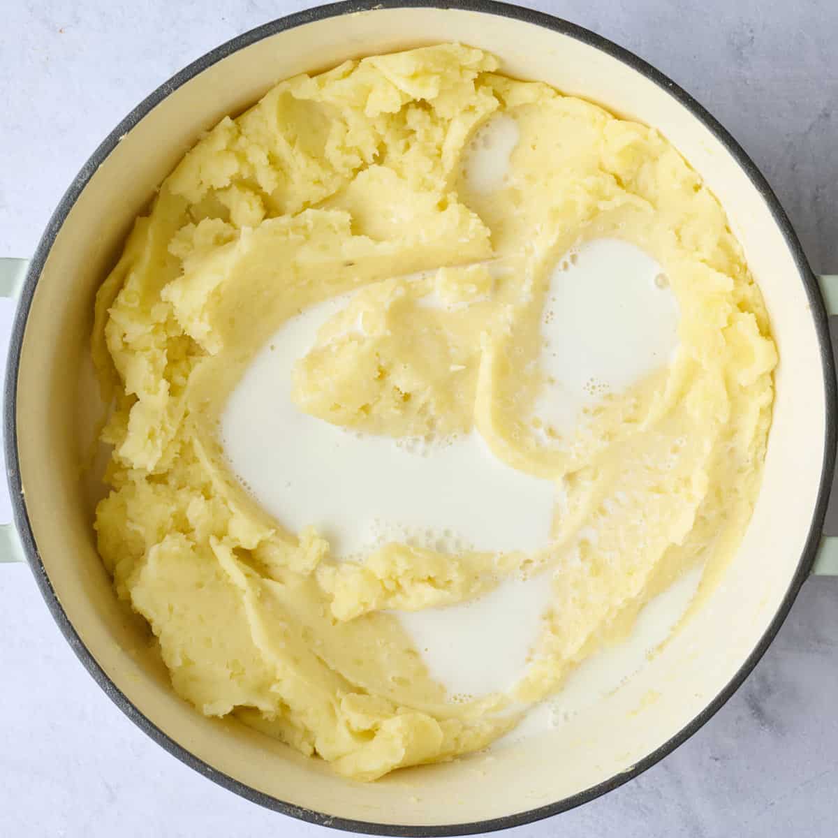 Milk added to mashed potatoes before mixing.