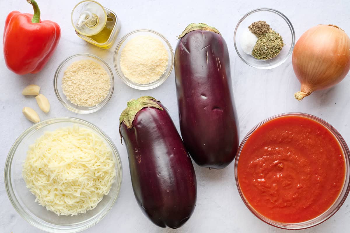 Ingredients for recipe: eggplant, crushed tomatoes, red pepper, garlic, onion, seasonings, oil, breadcrumbs, and parmesan.