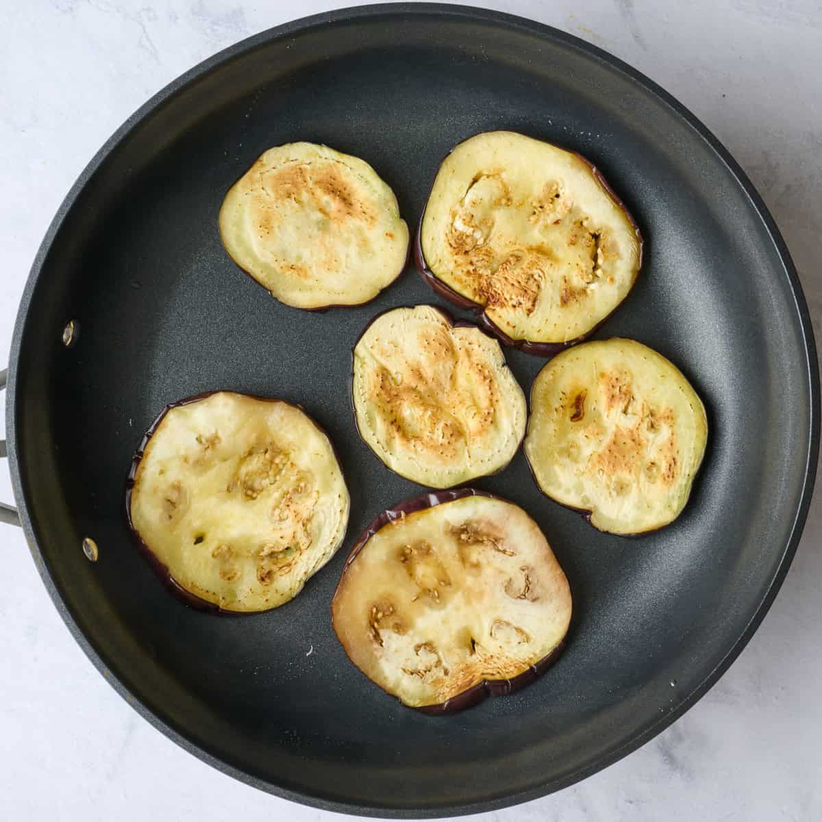 Pan cooked eggplant slices after flipping.