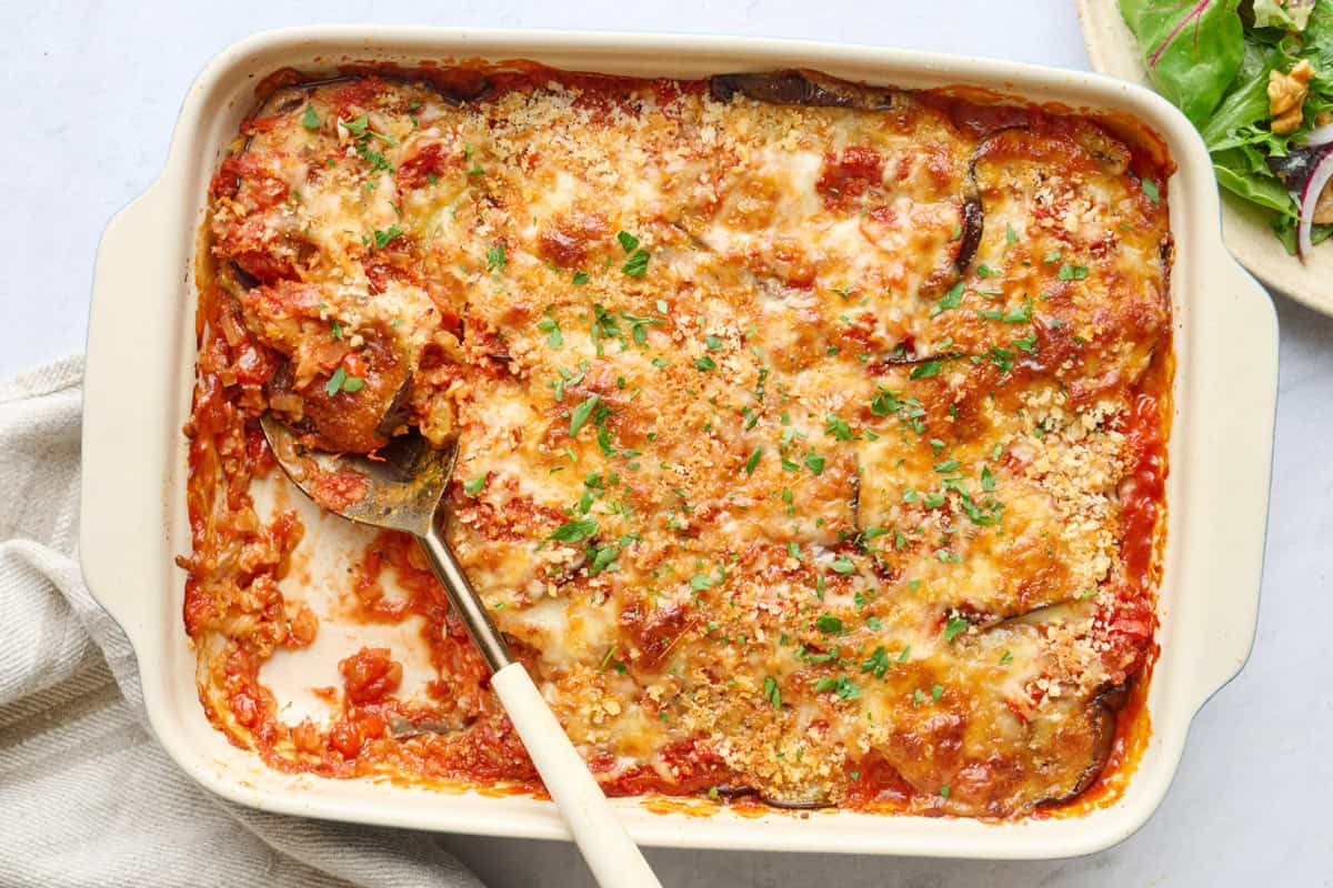 Easy Eggplant casserole in baking dish with serving removed and serving spoon dipped inside.