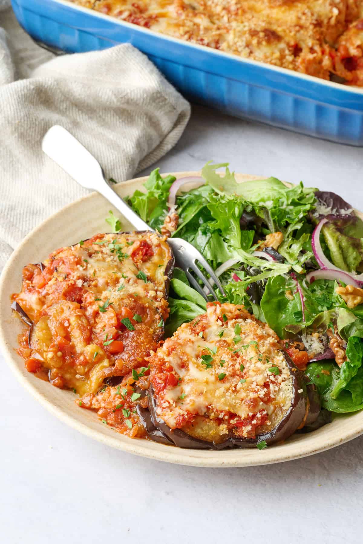 Eggplant casserole on a plate with a spring salad.