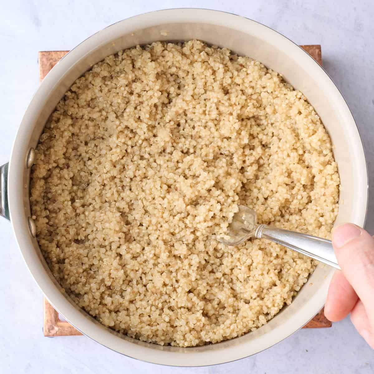 Fluffing quinoa after cooking in a pot.