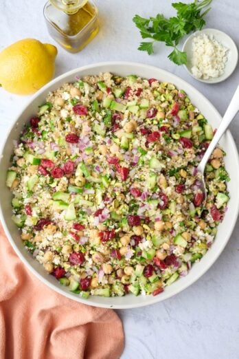 Jennifer Aniston salad recipe in a serving bowl filled with quinoa, chickpeas, dried cranberries, fresh herbs, and veggies.