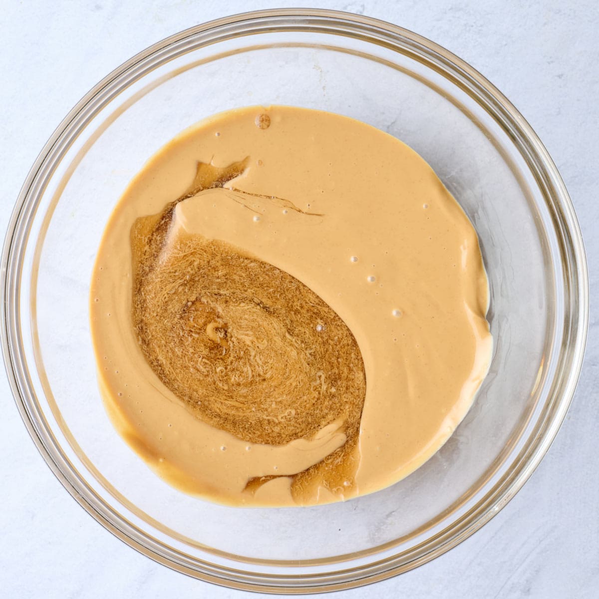 Peanut butter in a bowl after melting with maple syrup and vanilla added.