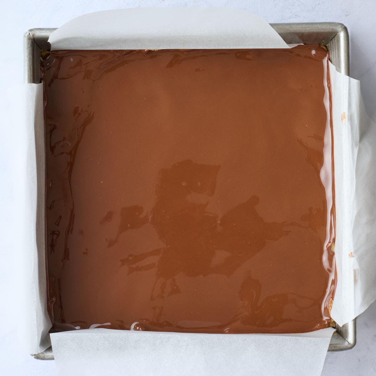 Chocolate poured over cookie base before chilling.