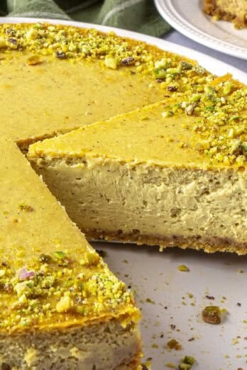 Best pistachio cheesecake recipe on a plate with pie spatula lifting up a slice.