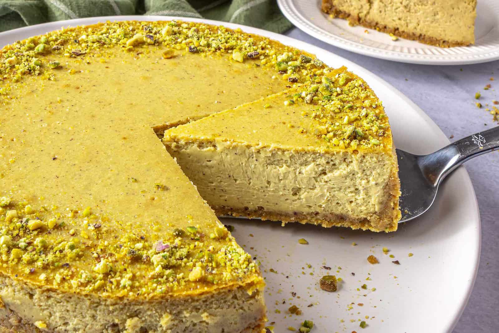 Best pistachio cheesecake recipe on a plate with pie spatula lifting up a slice.