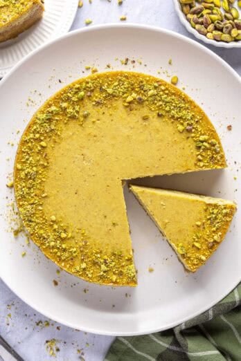 Baked pistachio cheesecake recipe on a platter with a slice cut out.
